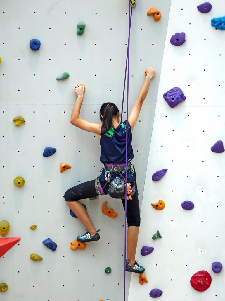 jeune grimpeuse sur mur d&#039;escalade